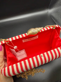 The selected item is the Shiraleah Marina Red Striped Lobster Minaudière Clutch.This nautical-inspired evening bag features a structured box silhouette dressed in bold red and white vertical stripes. It is accented by a prominent, bright blue embroidered